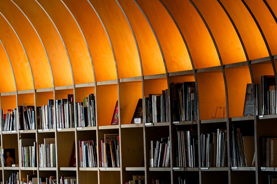 Tall bookshelves filled with novels in a quiet reading room with warm lamp light
