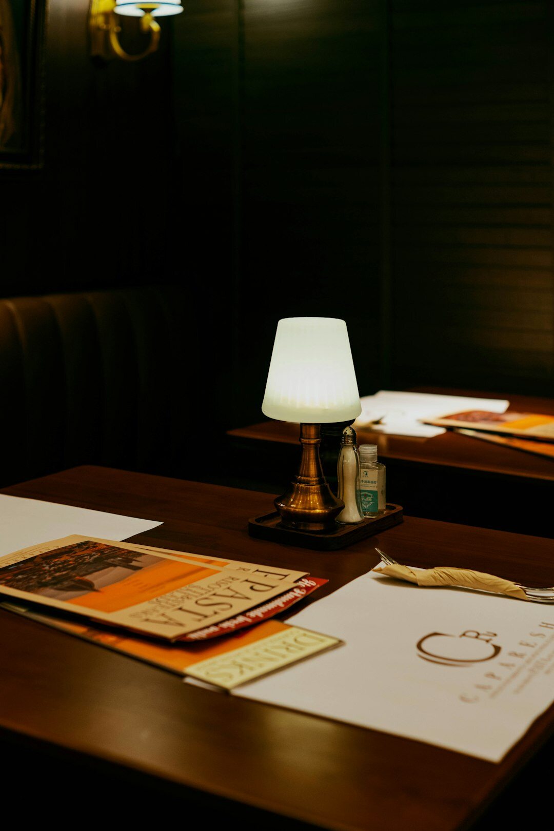 Old wooden writing desk with typewriter, papers and a dim desk lamp at night